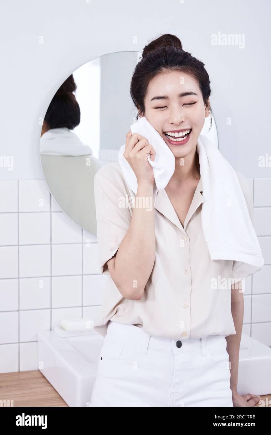 Sommer-Lifestyle, junge koreanische asiatische Frau, die sich auf das Waschbecken im Bad lehnt und das Gesicht abwischte Stockfoto