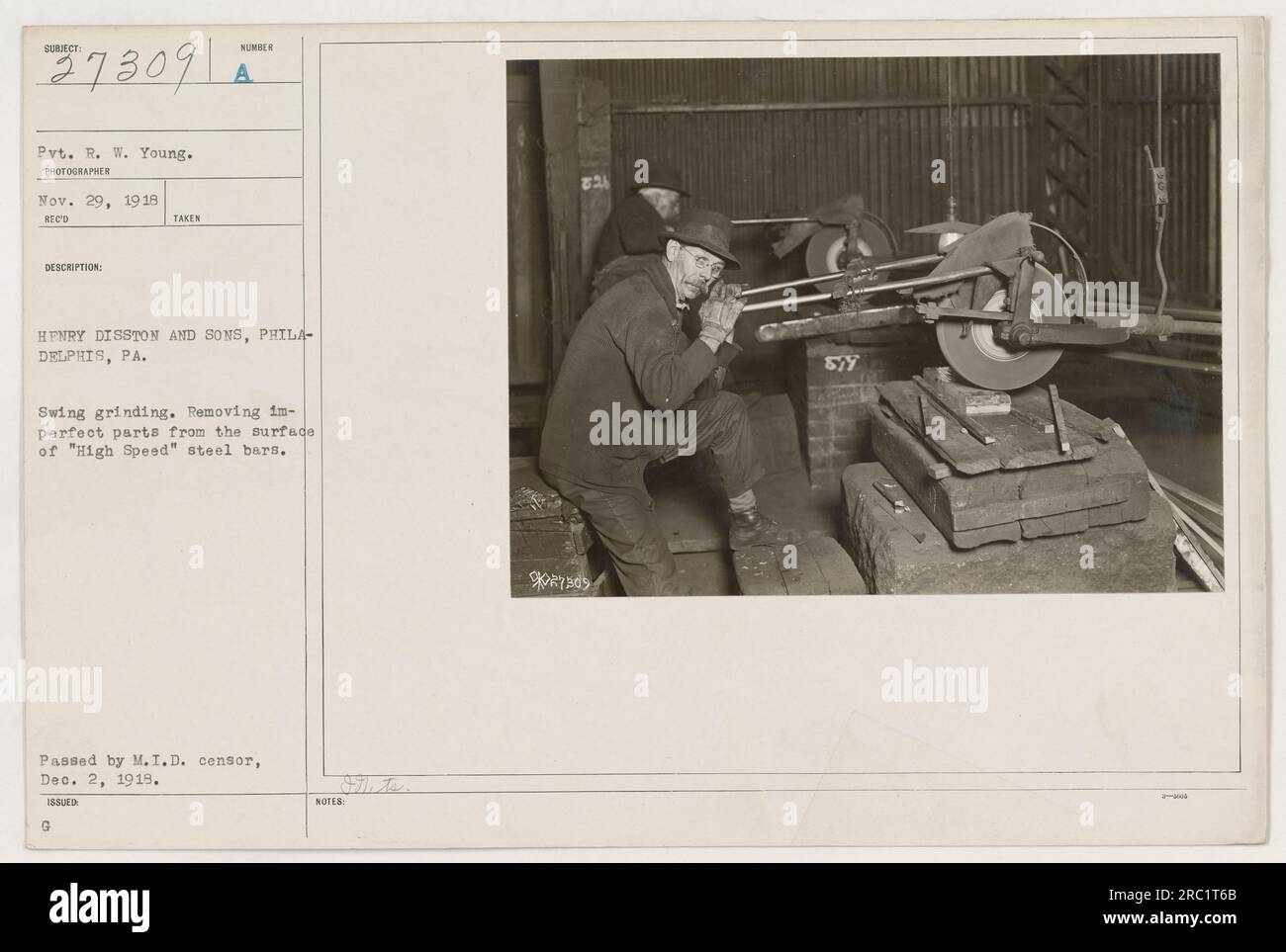 Gefreiter R. W. Young in Uniform, gefangen im Ersten Weltkrieg. Er arbeitet in einem Werk von Henry Disston and Sons in Philadelphia, Pennsylvania. Das Foto zeigt Pvt. R. W. Young, der im Schwenkschleifen tätig ist, während er unvollkommene Teile von der Oberfläche von „High Speed“-Stahlstangen entfernt. Dieses Foto wurde am 2. Dezember 1919 vom Zensor des Militärgeheimdienstes freigegeben. Stockfoto