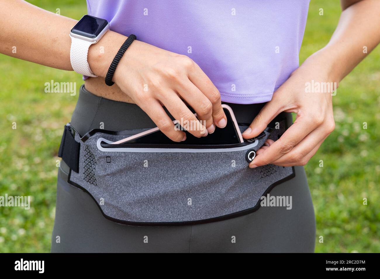 Fitness-Läuferin macht sich mit Smartwatch und Smartphone-Halterung gürteltasche für das Laufen bereit. Sportlerin mit tragbarem Tech Activity Tracker. Stockfoto