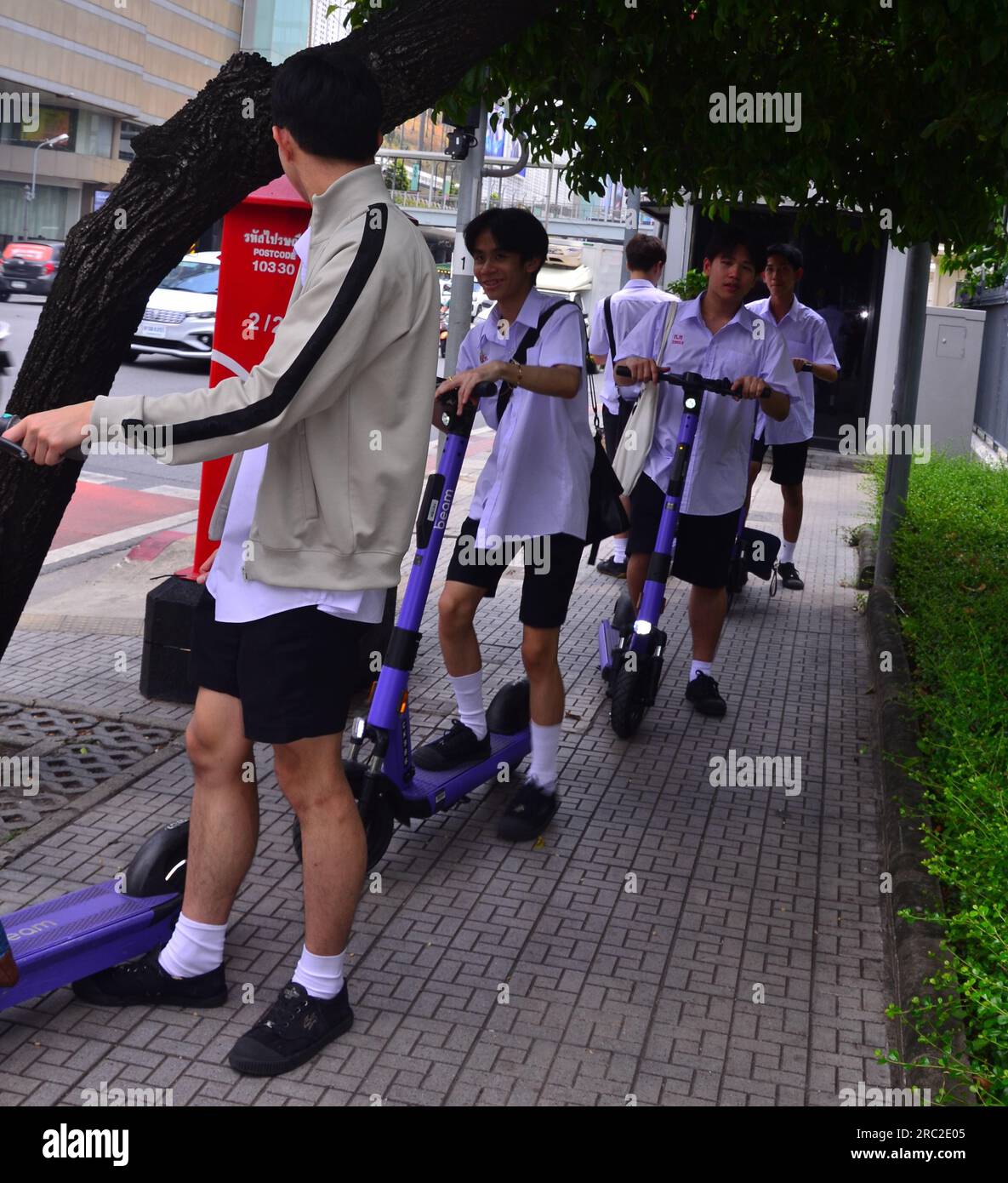 Jugendliche Jungen im Alter von 14-16 Jahren fahren mit E-Bikes auf dem Bürgersteig im Zentrum von Bangkok, Thailand, Südostasien. Dies stellt eine Gefahr für Fußgänger dar, und ob dies zugelassen werden soll, ist in vielen Ländern eine Frage der Diskussion. Stockfoto