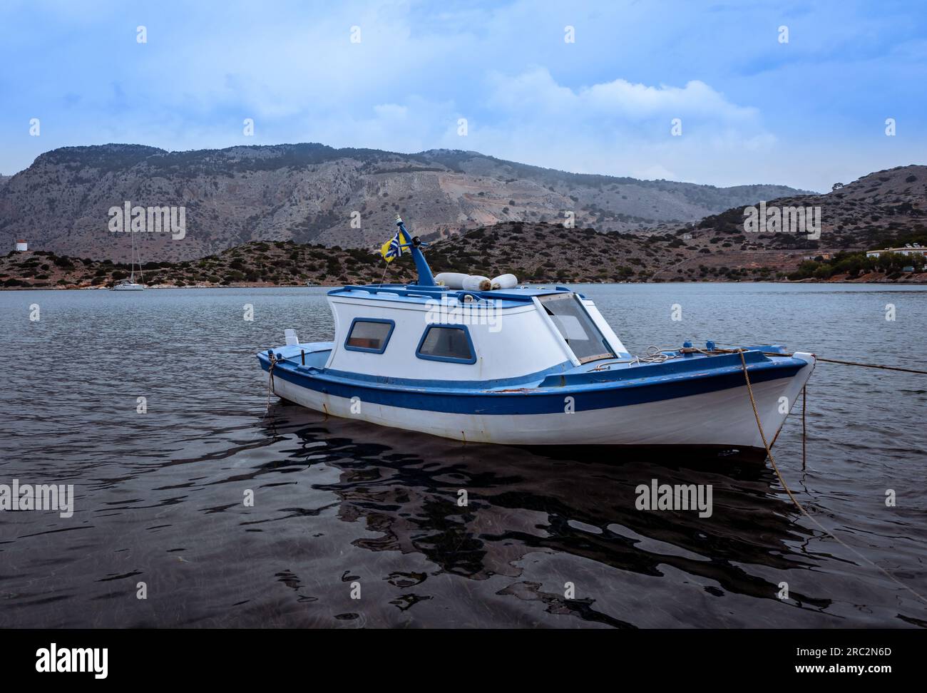 Symi, Griechenland - 30. Mai 2023: Ein kleines traditionelles griechisches weißes und blaues Fischerboot auf dem Wasser in Symi, Griechenland. Stockfoto