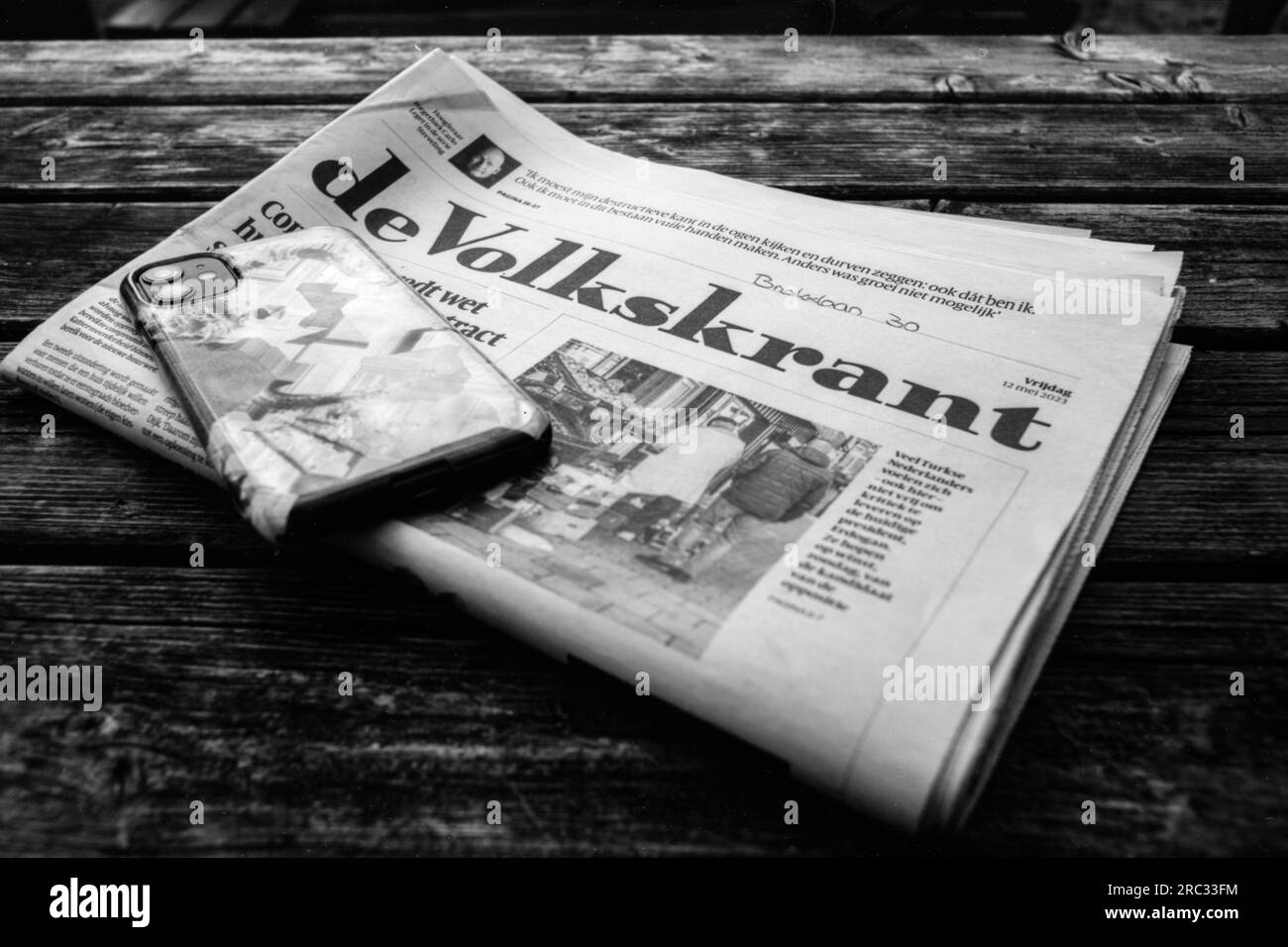 Zeitung De Volkskrant auf einem Tisch auf der Strandterrasse, die von einem Gast gelesen wird. Tilburg, Niederlande. Stockfoto
