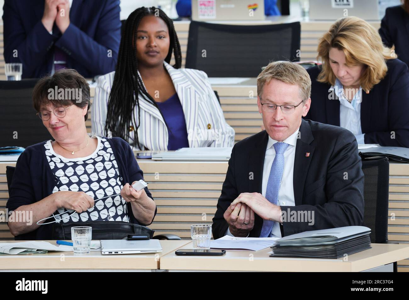 12. Juli 2023, Schleswig-Holstein, Kiel: Daniel Günther (CDU, Front r), Ministerpräsident von Schleswig-Holstein, sitzt auf der Regierungsbank neben Monika Heinold (Bündnis 90/die Grünen, Front l), Finanzministerin und Stellvertretende Ministerpräsidentin Aminata Touré (Bündnis 90/Grüne, Back l), Ministerin für Soziales, Jugend, Familie, Senioren, Integration und Gleichstellung. Und Kerstin von der Decken (CDU), Ministerin für Justiz und Gesundheit, auf einer Sitzung des landesparlaments. Foto: Christian Charisius/dpa Stockfoto