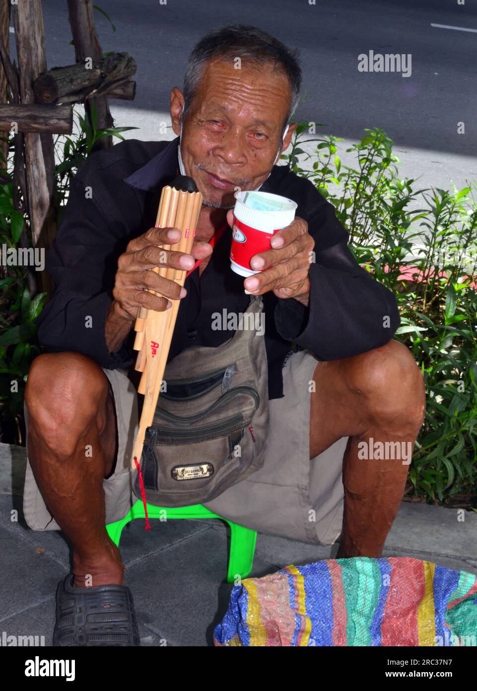 Ein älterer Mann spielt ein kleines Pipes-Musikinstrument und bettelt um Geld in Zentral-Bangkok, Thailand, Südostasien Stockfoto