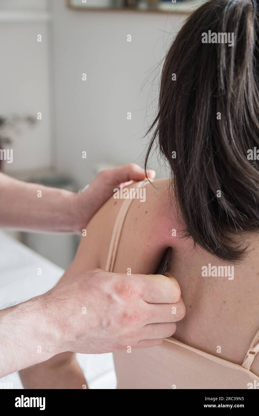 Junge Weiße, Die Eine Körperbehandlung Bekommt. Therapeut macht Hautkratztechnik. Chinesische Technik, Gua sha, zur Schmerzlinderung und -Behandlung Stockfoto