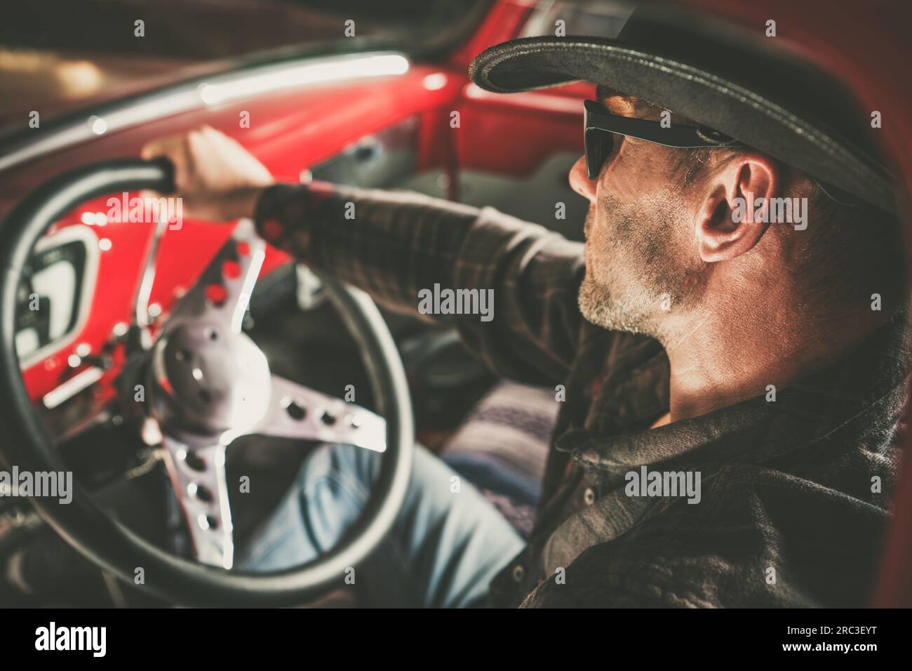 Der Kaukasische Amerikanische Cowboy Hinter Dem Klassischen Pickup-Rad. Amerikanisches West-Thema. Stockfoto