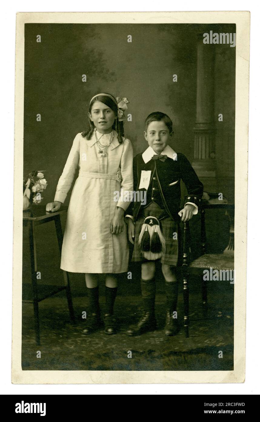 Die originale, charmante Postkarte der frühen 1900er Jahre mit 2 attraktiven jungen, edwardianischen schottischen Kindern, Bruder und Schwester in ihrer schicken Kleidung, trägt den Jungen in einem schottischen Kilt, für einen besonderen Flaggentag, um 1910. Musselburgh, East Lothian, Schottland, an der Küste des Firth of Forth, Großbritannien Stockfoto