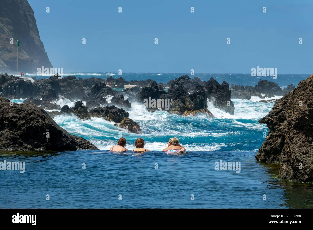 Touristen schwimmen in den natürlichen Meerwasser-Lava-Pools in Porto Moniz, Insel Madeira, Portugal Stockfoto