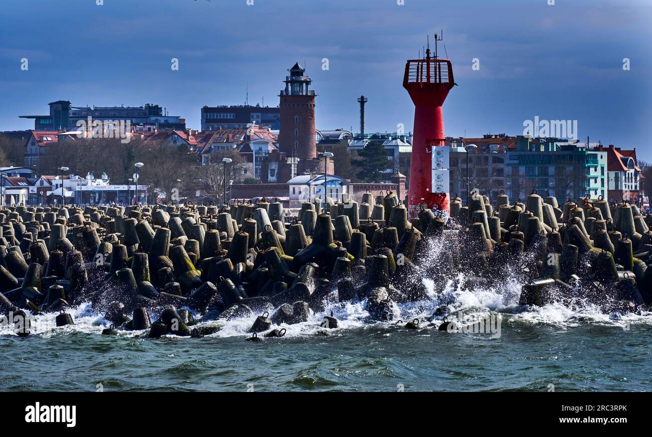 Kolberg, Polen, 20. April 2023: Wellenbrecher aus Betonpolygonen und Navigationsmarkierungen vor dem Leuchtturm im Hafen der polnischen Stadt o Stockfoto