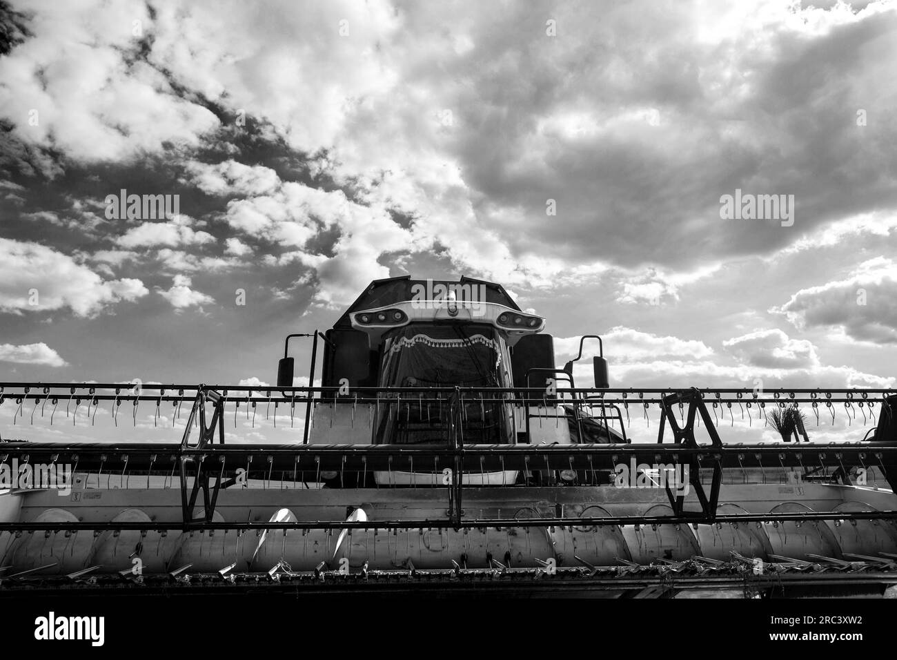 Ein moderner Mähdrescher steht während der Ernte auf dem Feld. Ansicht von unten mit Weitwinkelobjektiv am schwenkbaren Rahmen des Draper-Mähdreschers Stockfoto