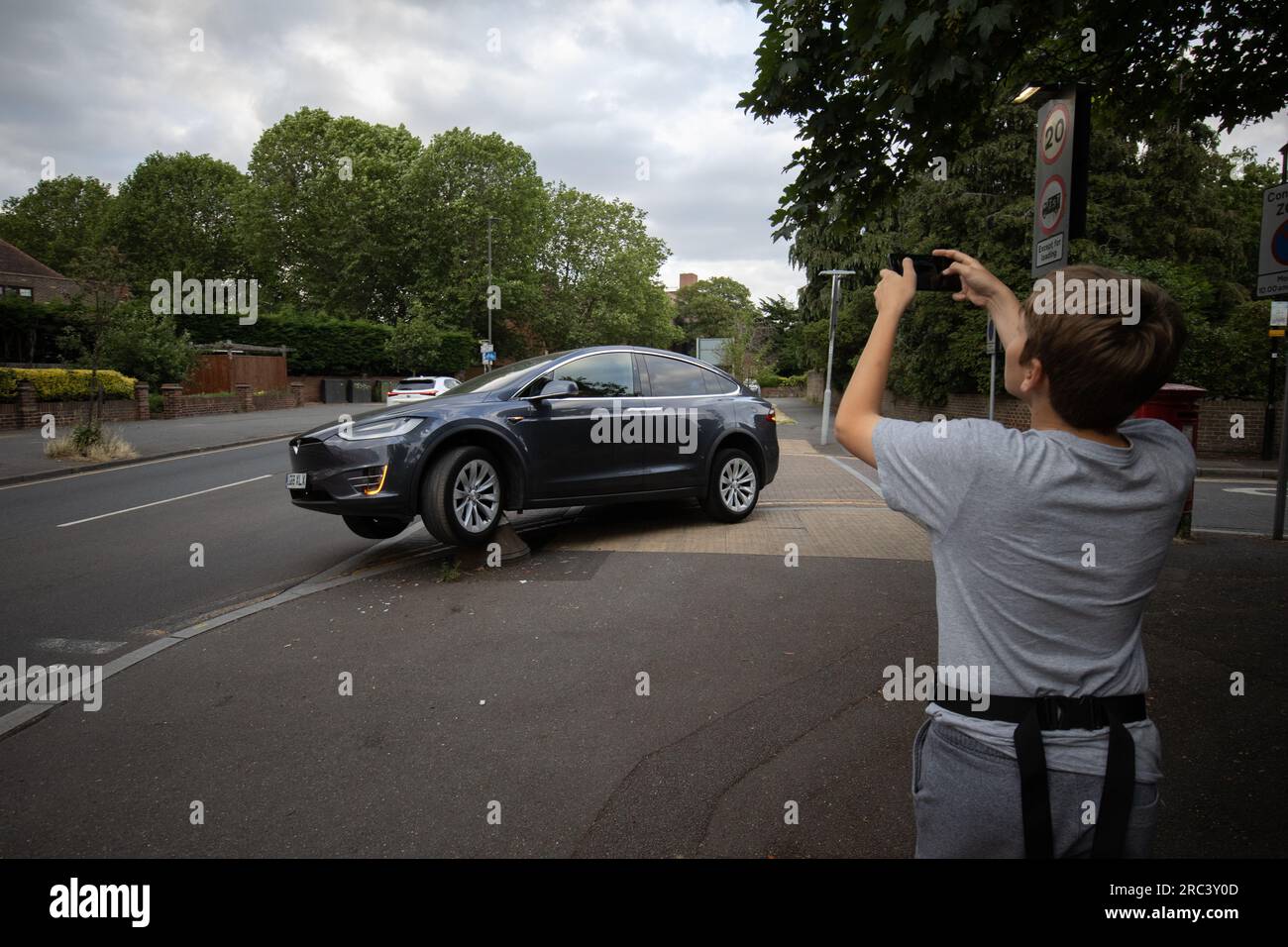 Tesla sitzt fest, nachdem er versehentlich über einen Poller an der Ecke einer Wohnstraße in South Wimbledon, London, England, gefahren ist Stockfoto