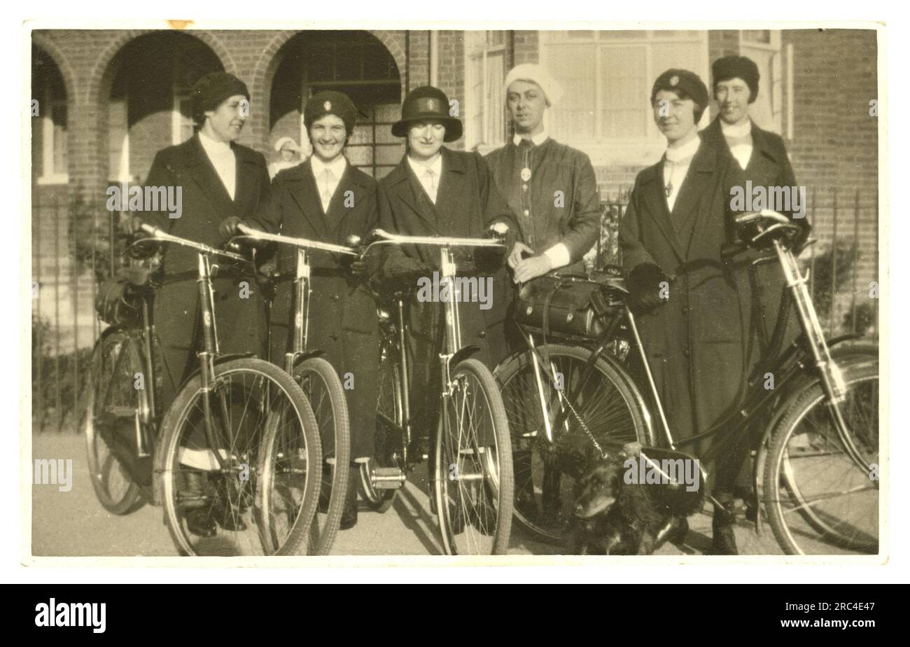 Originale Postkarte aus dem Jahr WW1 mit einer Gruppe von fröhlichen Bezirksschwestern mit Fahrrädern, die Abzeichen des Queen's Institute of District Nurses (QNI) auf Hüten tragen - arbeiten an der Heimatfront, um 1915, Großbritannien Stockfoto