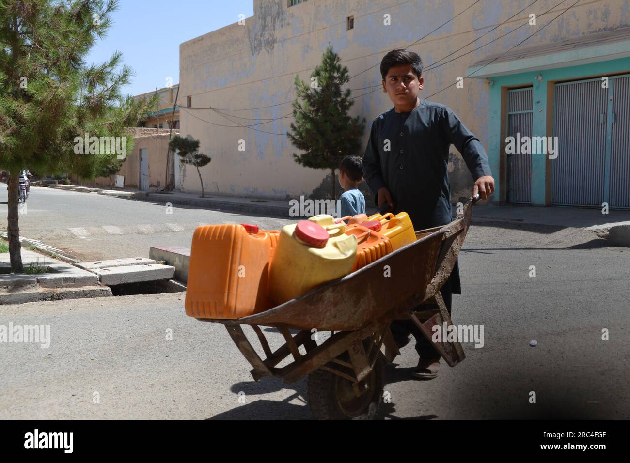 KANDAHAR, 12. Juli 2023 (Xinhua) -- ein afghanisches Kind trägt Fässer mit sauberem Wasser in der Provinz Kandahar, Afghanistan, 12. Juli 2023. (Foto: Arghand/Xinhua) Stockfoto