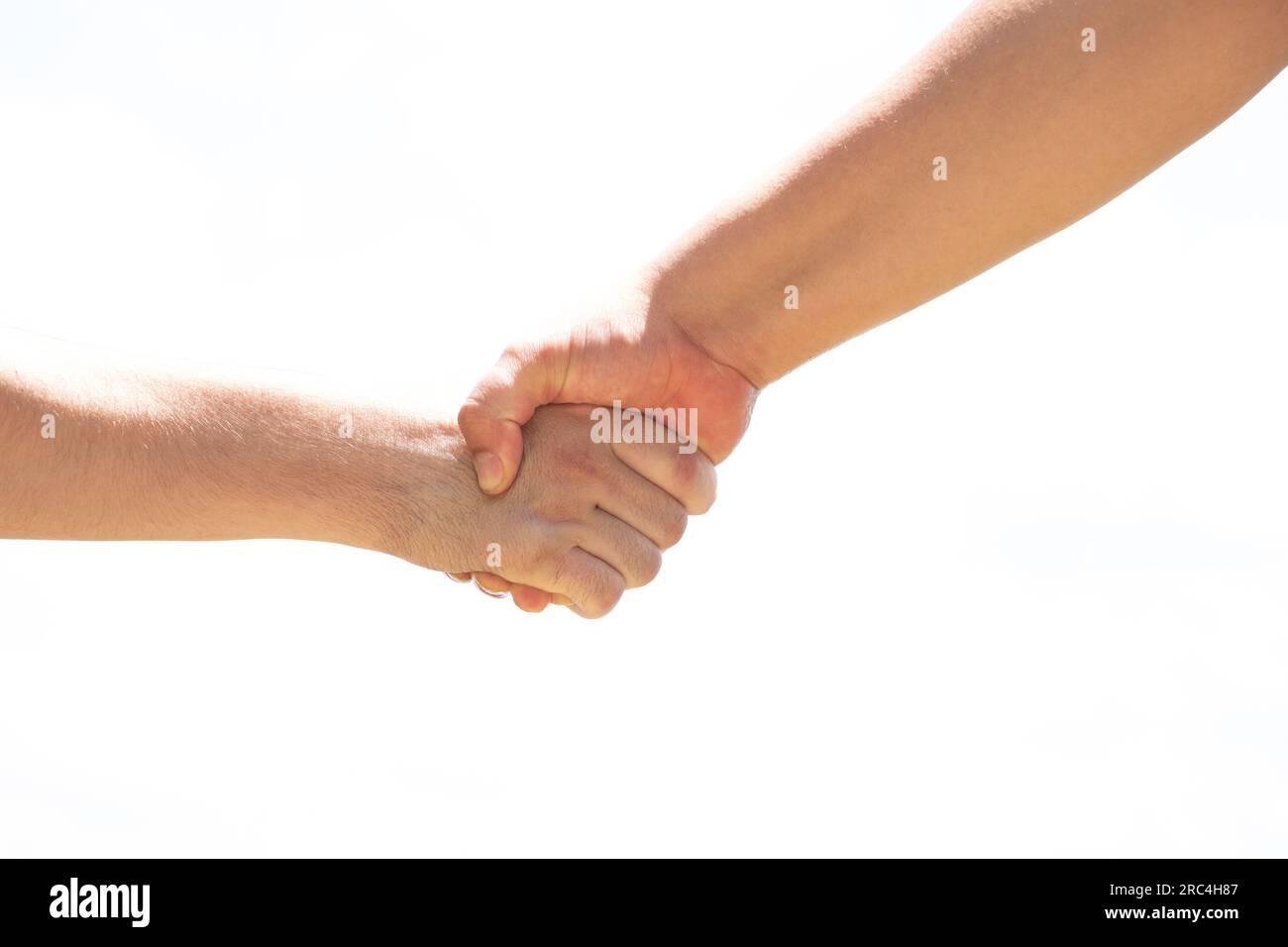 Zwei Männer hielten sich die Hände auseinander, als Zeichen der Freundschaft und Begrüßung, ein Händedruck vor dem Hintergrund des Himmels in der Sonne auf der Straße, Stockfoto