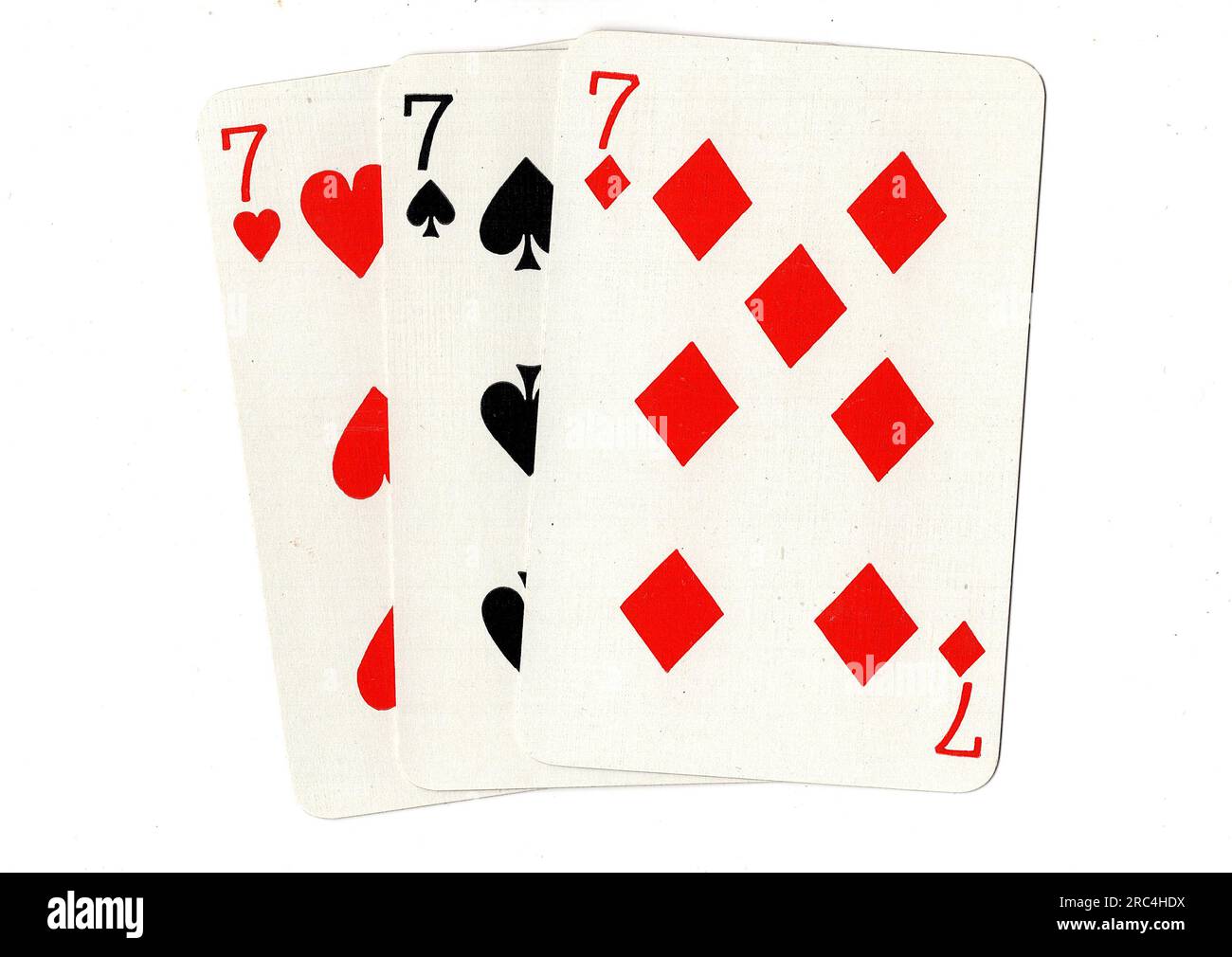 Vintage-Spielkarten mit drei Siebenen auf weißem Hintergrund. Stockfoto