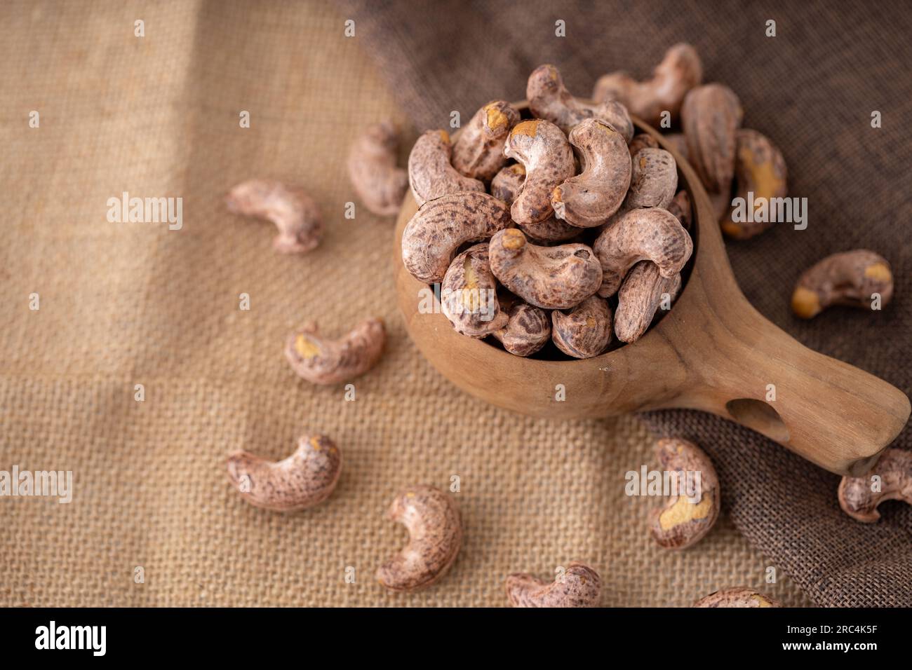 Geröstete Kaschu-Nüsse und -Hälften in einer Holzschüssel auf dem Tisch. Makro Studio hat hausgemachte, gebratene, gesalzene Cashews in einem Korb und Löffel Frühstück auf SA gemacht Stockfoto