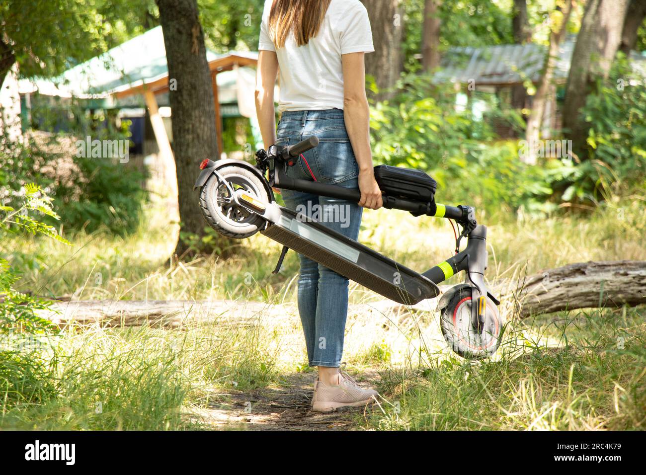 Im Sommer hält ein Mädchen einen elektrischen Roller in den Parkanlagen der Ukraine, im städtischen Elektrotransport Stockfoto