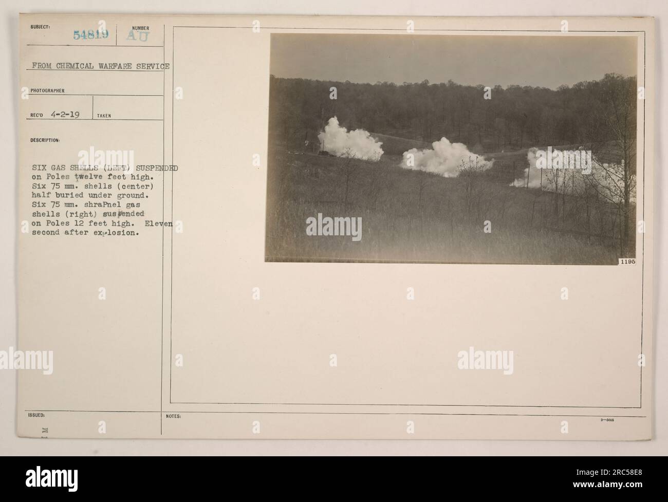 Die Abbildung zeigt sechs Gasschalen, die auf Polen, die drei Meter hoch sind, auf der linken Seite aufgehängt sind. In der Mitte befinden sich sechs 75-mm-Schalen, die teilweise unterirdisch vergraben sind. Auf der rechten Seite befinden sich sechs 75-mm-Schrapnell-Gasschalen, die auf zwölf Fuß hohen Pfosten aufgehängt sind. Das Foto wurde am 2. April 1919 von einem Chemical Warfare Service Fotografen aufgenommen und hat die Nummer 54819. Elf Sekunden nach der Explosion wurde das Bild aufgenommen. Die Beschreibung und die zusätzlichen Anmerkungen zum Bild haben die Codenummern 1196 bzw. DIE H-ANMERKUNGEN 1196. Stockfoto