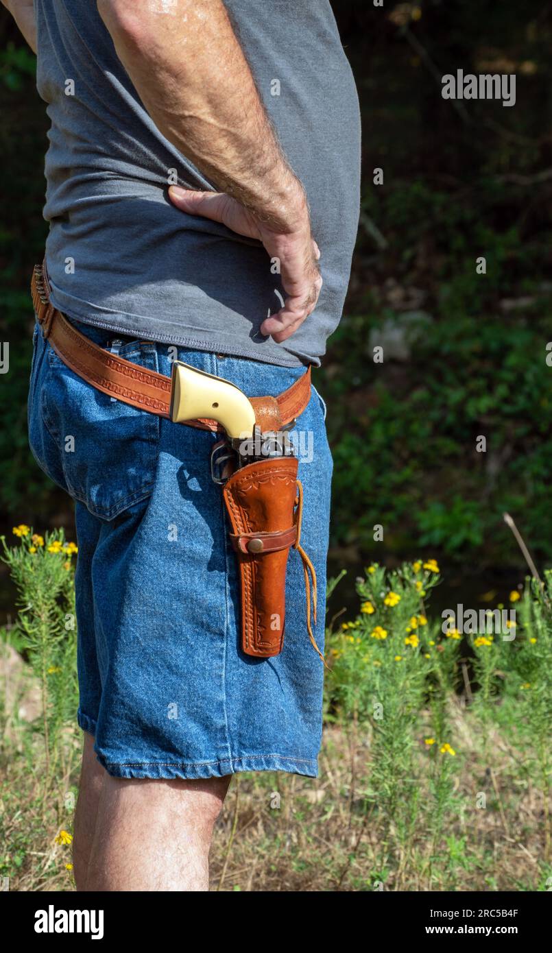 Ein nicht identifizierbarer Mann modelliert eine 22-Pistole in einem Lederholster in Missouri. Bokeh. Stockfoto