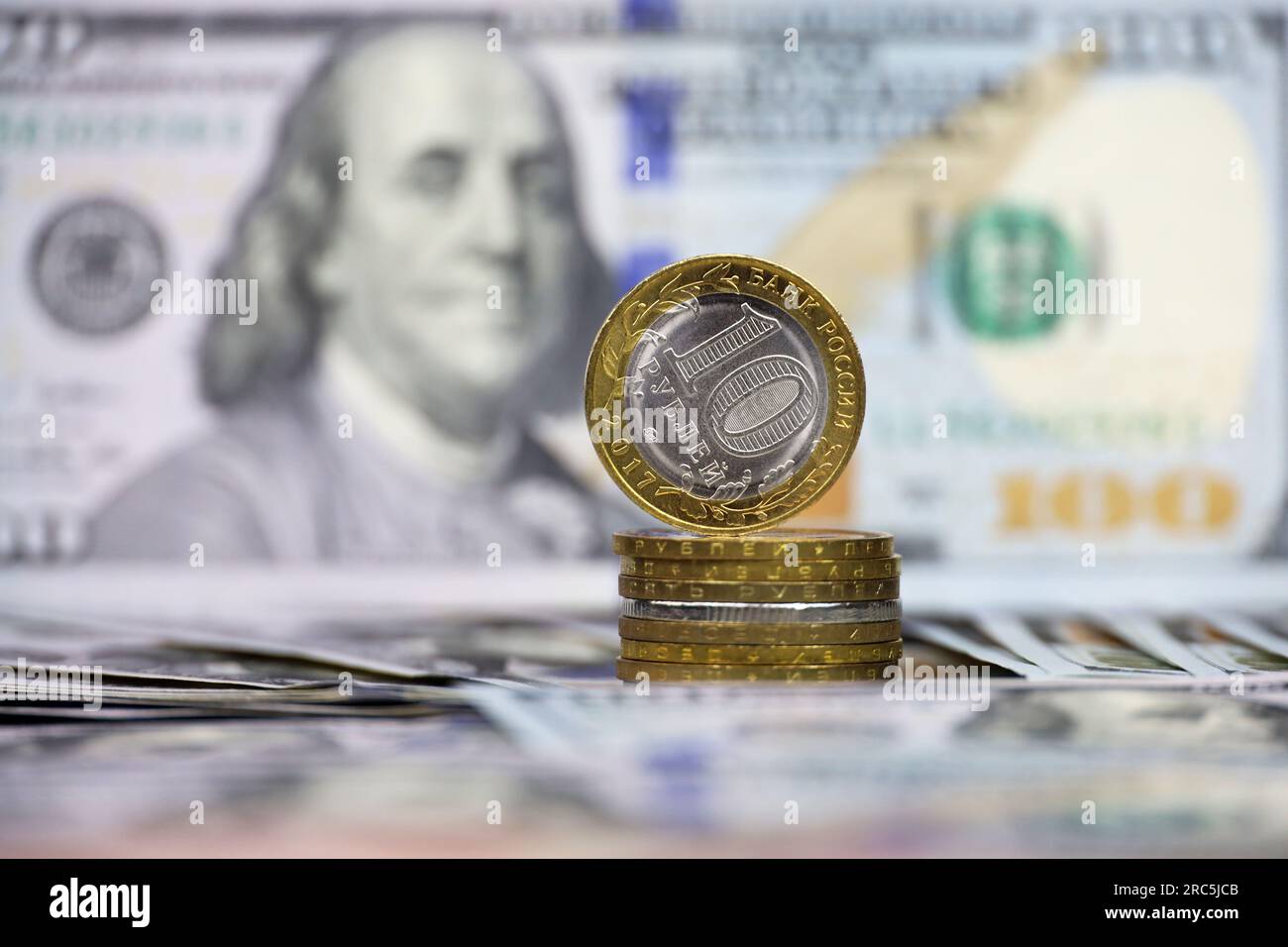 Russische Rubel-Münzen auf dem Hintergrund von US-Dollar. Konzept des Wechselkurses, amerikanische Sanktionen gegen die Wirtschaft Russlands, fallender Rubel Stockfoto