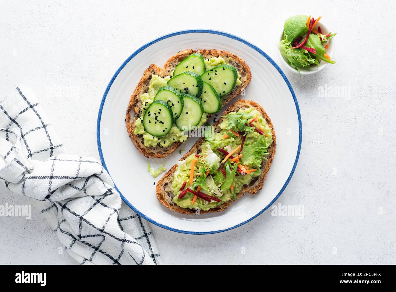 Vegane Avocado-Toasts mit Garnierung aus Gurken und frischem grünen Salat mit geriebener Karotte und roher Rüben. Sauberes Essen, Diätkonzept. Draufsicht Stockfoto