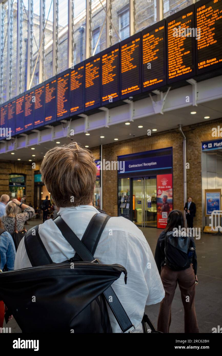 Der Rail Commuter sieht die Abfahrtsschilder an der Londoner Kings Cross Station. Der Pendler wartet am Bahnhof Kings Cross in London auf einen Zug. Stockfoto