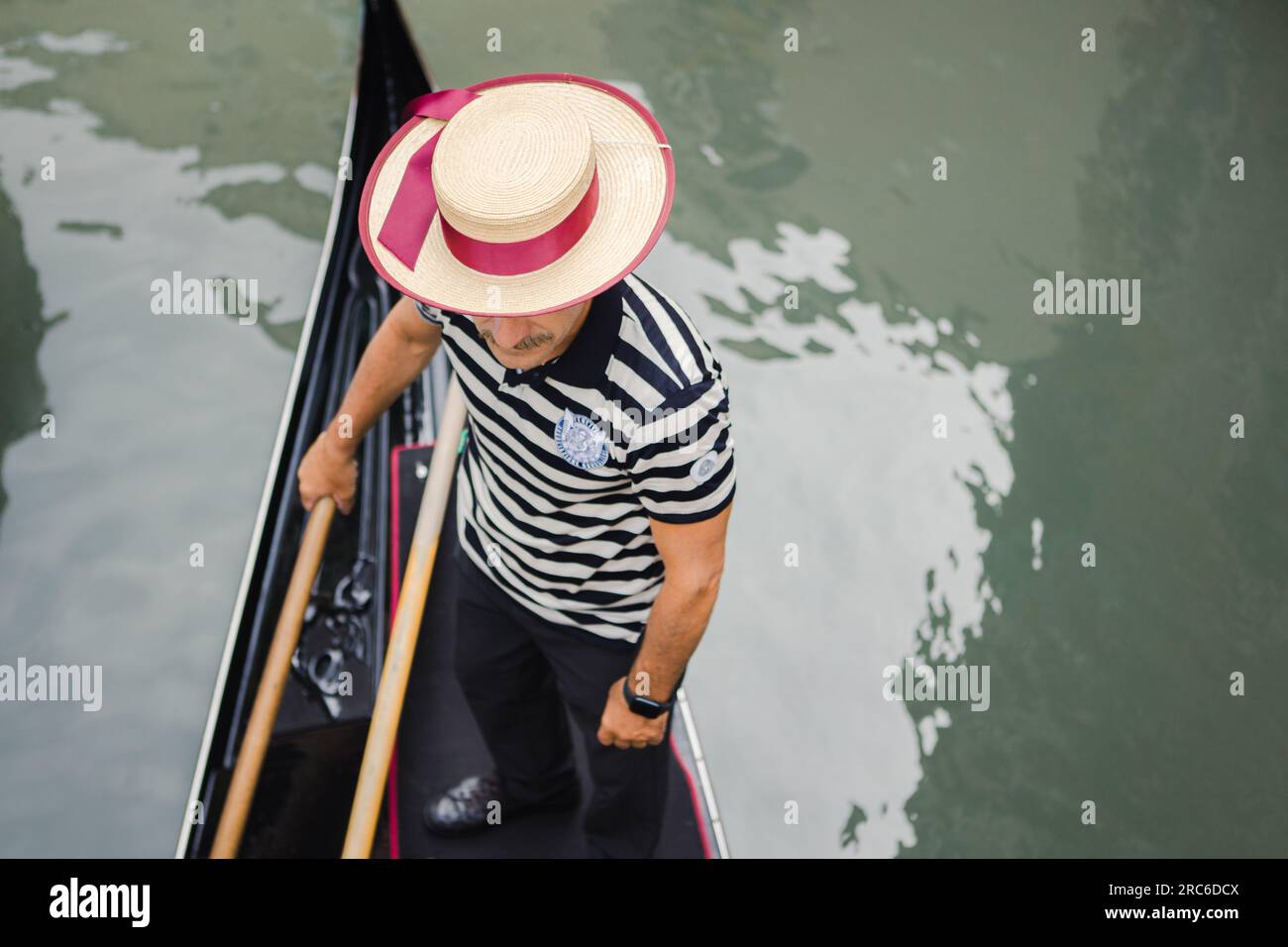 Gondoliere mit Gondolierhut auf einer Gondel, die in Venedig, Italien rudert Stockfoto