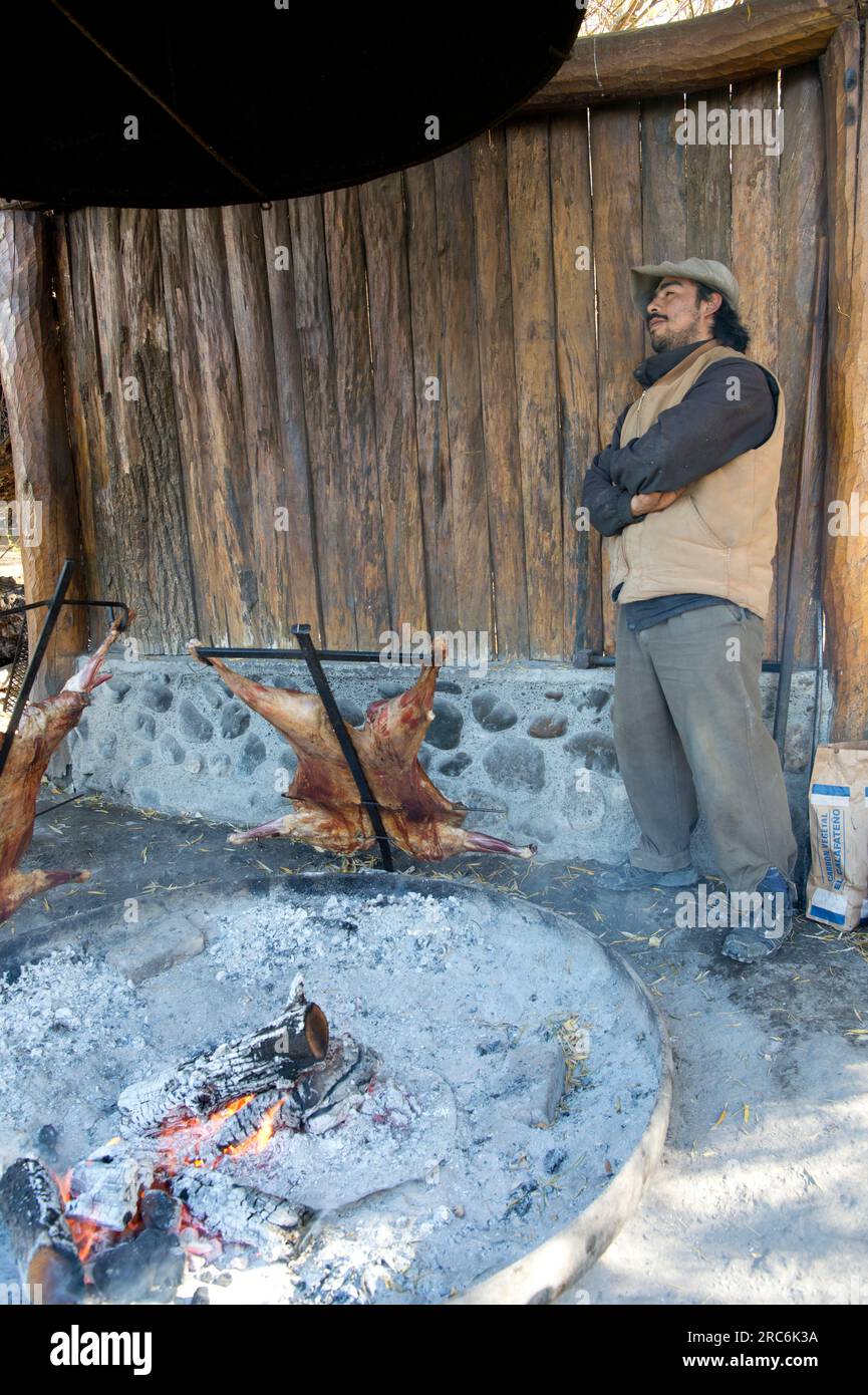 Argentinischer Gaucho, der Lamm über einem offenen Feuer in Südpatagonien, Argentinien, brät Stockfoto