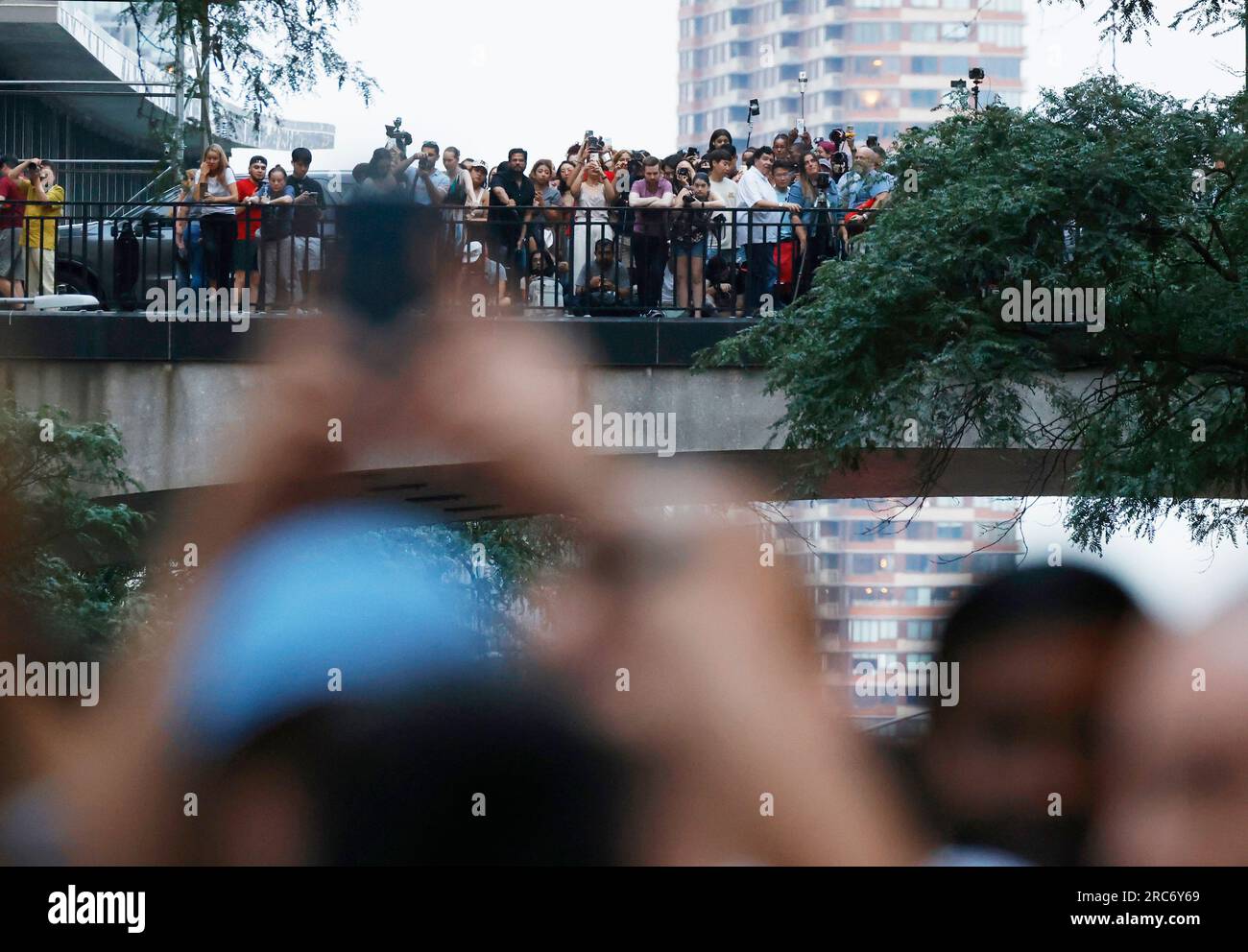 New York, Usa. 12. Juli 2023. Auf der 42. Street treffen sich Feier mit Kameras und Handys, um einen Sonnenuntergang in Manhattan zu erleben, der am Mittwoch, den 12. Juli 2023, aufgrund des bewölkten Himmels und der Wolkendecke in New York City enttäuscht wurde. Der Sonnenuntergang über Manhattan findet zweimal im Jahr statt, wenn die untergehende Sonne genau auf Manhattans Straßennetz ausgerichtet ist. Foto: John Angelillo/UPI Credit: UPI/Alamy Live News Stockfoto