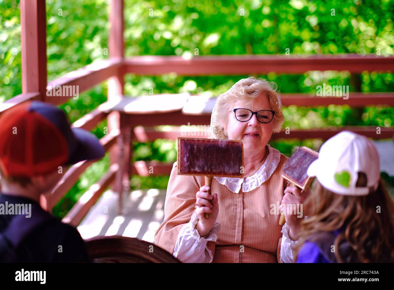 Toronto, Ontario, Kanada - 28. Mai 2023: Eine Seniorin, die Kindern während ihres Besuchs im Pionierdorf Black Creek ein Werkzeug aus dem Jahr 1860er vorstellt. Stockfoto