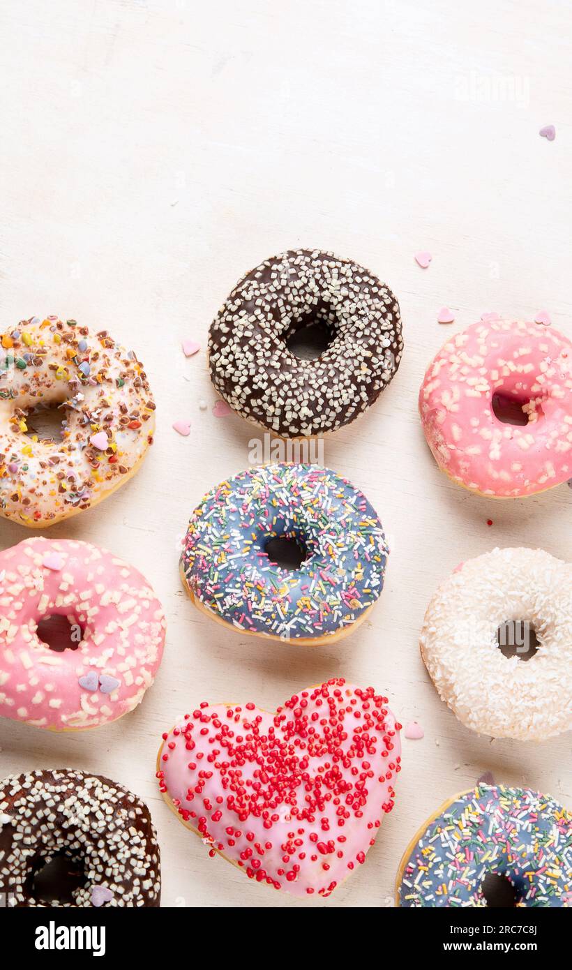 Donuts-Muster. Draufsicht auf verschiedene glasierte Donuts. Bunte Donuts mit Glasur. Verschiedene bunt glasierte Donuts mit Streuseln auf hellem Hintergrund Stockfoto