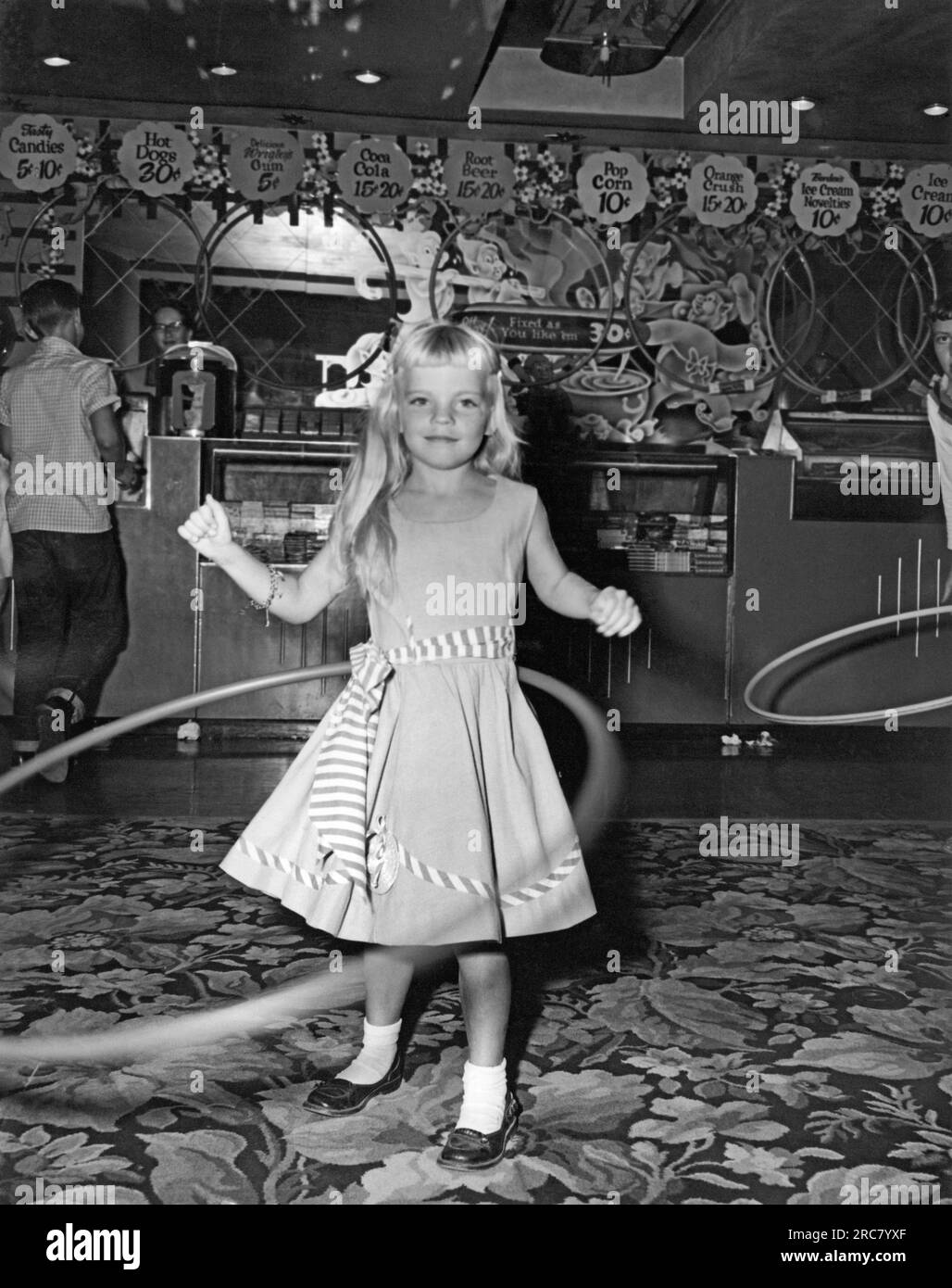 Vereinigte Staaten: 1958. Der Hula-Hoop-Wahnsinn durchkämmt das Land. Im ersten Jahr wurden in den USA über 100 Millionen Dollar verkauft. Dieser Wettbewerb fand in einer Kinolobby statt, als Popcorn einen Cent kostete und nur in einer Größe kam. Stockfoto