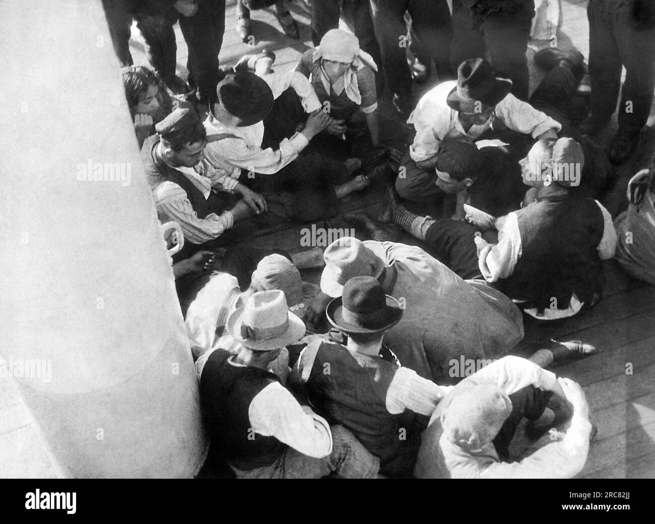 Südamerika: ca. 1930 europäische Juden an Bord eines Schiffes, die nach Südamerika auswandern, nachdem die USA die Einwanderung eingeschränkt hatten. Einige dieser Passagiere spielen „Belotte“, während andere zuschauen. Stockfoto