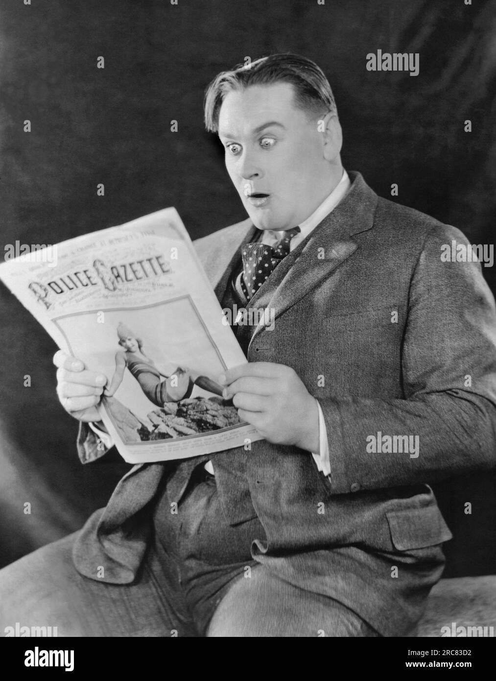 Los Angeles, Kalifornien: ca. 1920 Ein Mann ist überrascht von dem, was er in der Polizeizeitschrift liest. Stockfoto