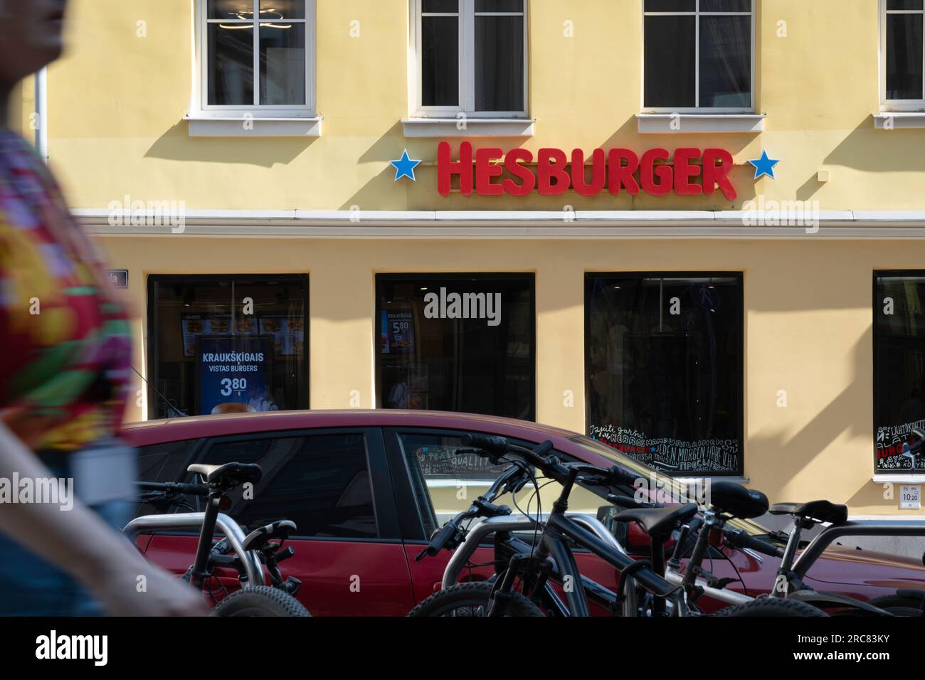 Hesburger Fast Food Restaurant in der Altstadt von Riga. Hesburger ist eine Fast-Food-Kette mit Sitz in Turku, Finnland. Eine Frau kommt vorbei Stockfoto