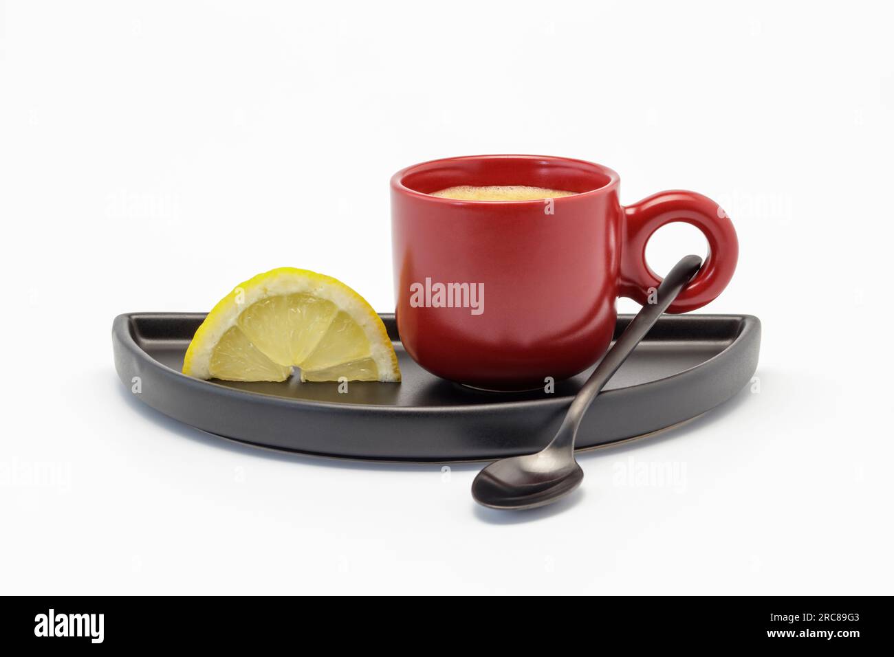 Rote Tasse gefüllt mit starkem Kaffee und ein Stück Zitronenausschnitt, natürliches Kopfschmerzmittel Stockfoto