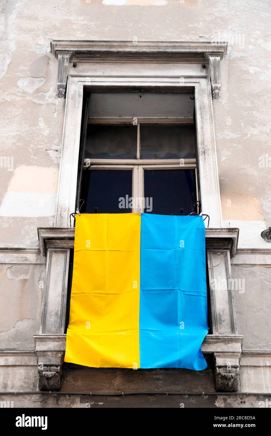Die ukrainische Flagge hängt aus einem Fenster in Padua, Italien. Unterstützung des ukrainischen Volkes gegen den russischen Angriff. Stockfoto