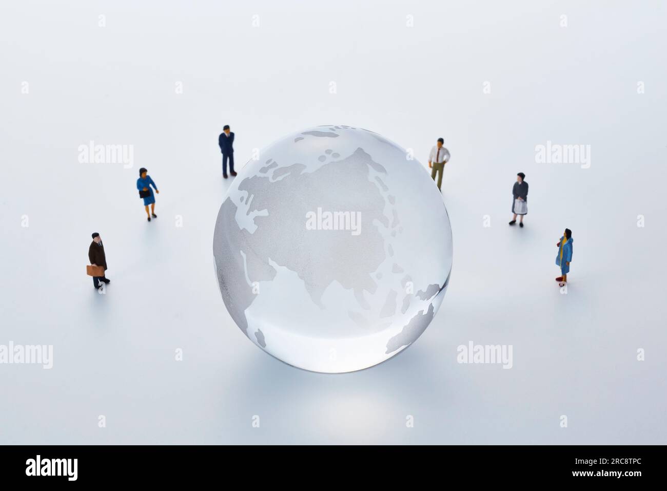 Menschen in Miniatur, die einen Globus umgeben Stockfoto