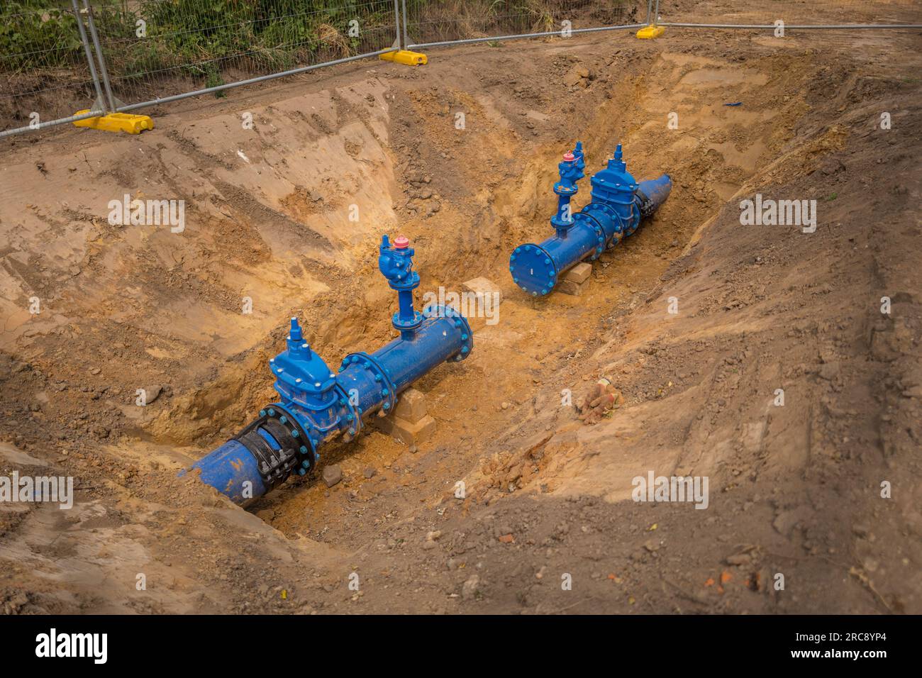 Neu installierte große Leitungswasserversorgungsklemme, die in einem ungeerdeten Graben freiliegend ist Stockfoto