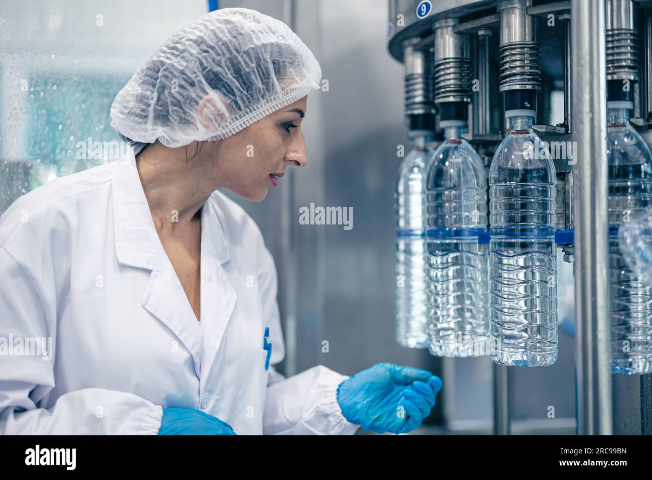 Arbeiter in der Trinkwasserfabrik. Weibliche Arbeiterinnen in der Getränkeproduktion Saubere Förderbänder Mineralwasserherstellung. Stockfoto