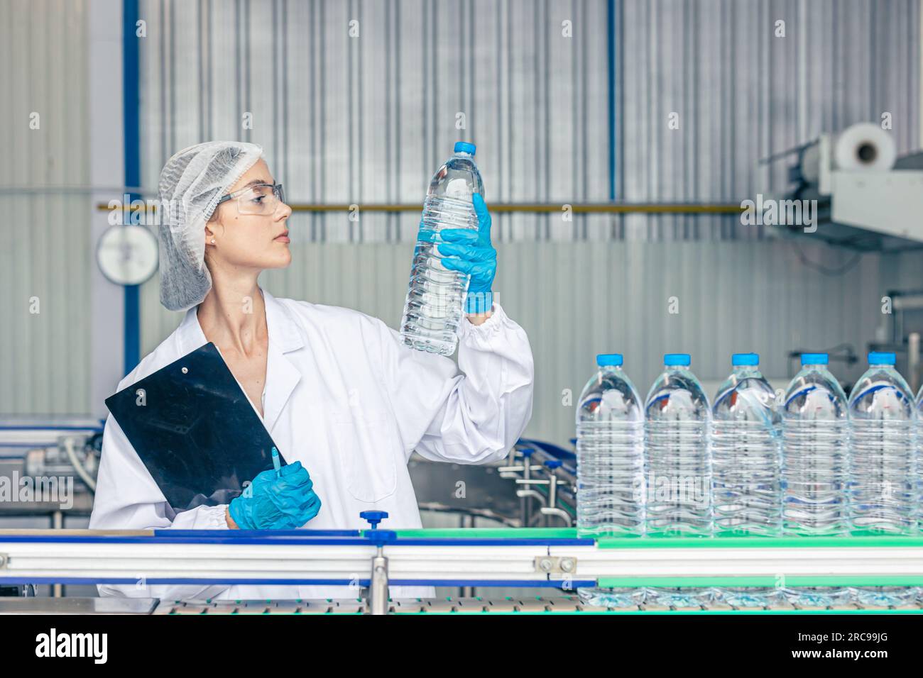 Arbeiter in der Trinkwasserfabrik. Weibliche Arbeiterinnen in der Getränkeproduktion Saubere Förderbänder Mineralwasserherstellung. Stockfoto