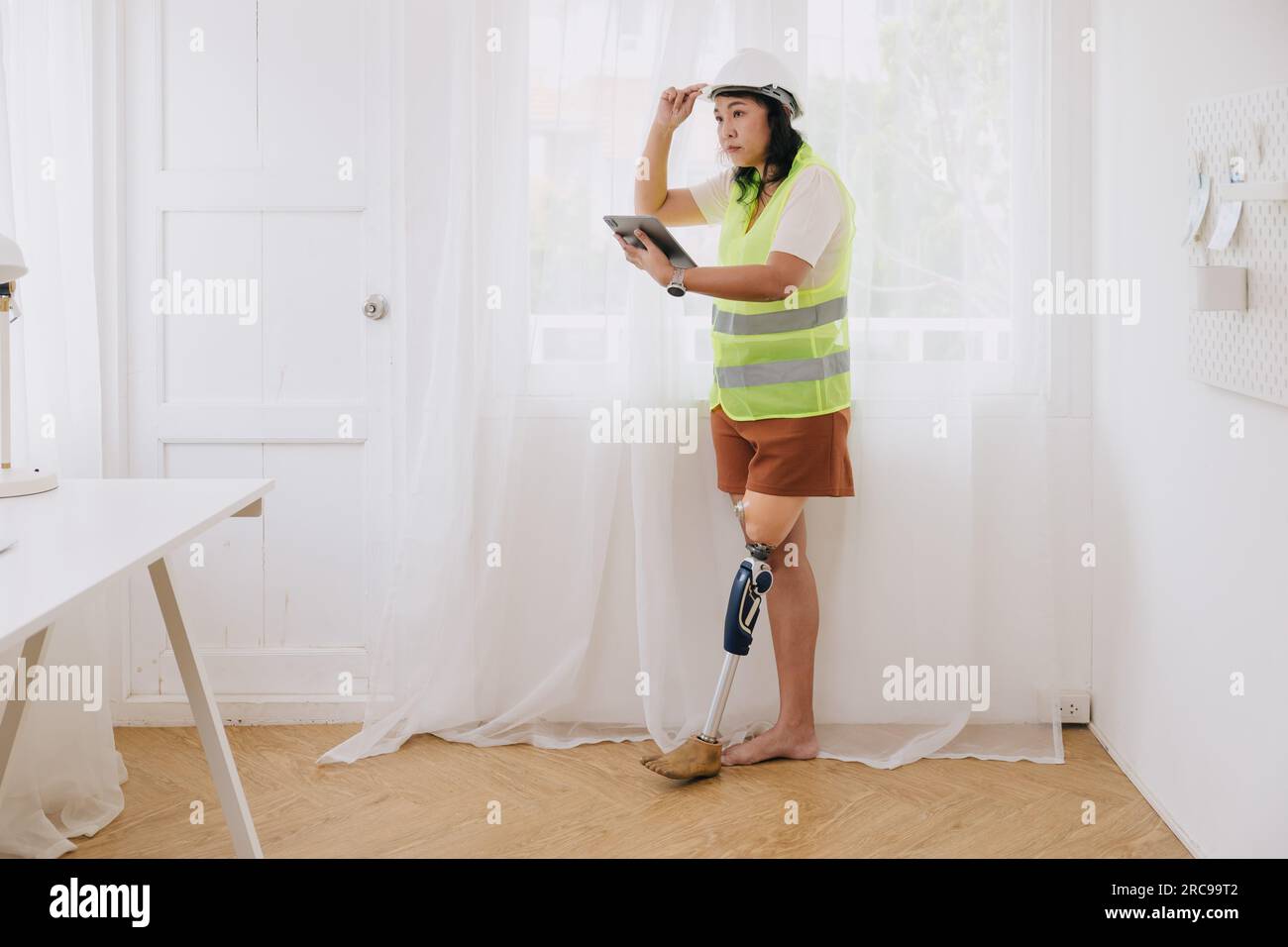 Professionelle Hausbauerin Behinderteningenieurin Frau mit Prothesen Bein intelligent arbeitendes Haus renovieren mit Sicherheit Stockfoto