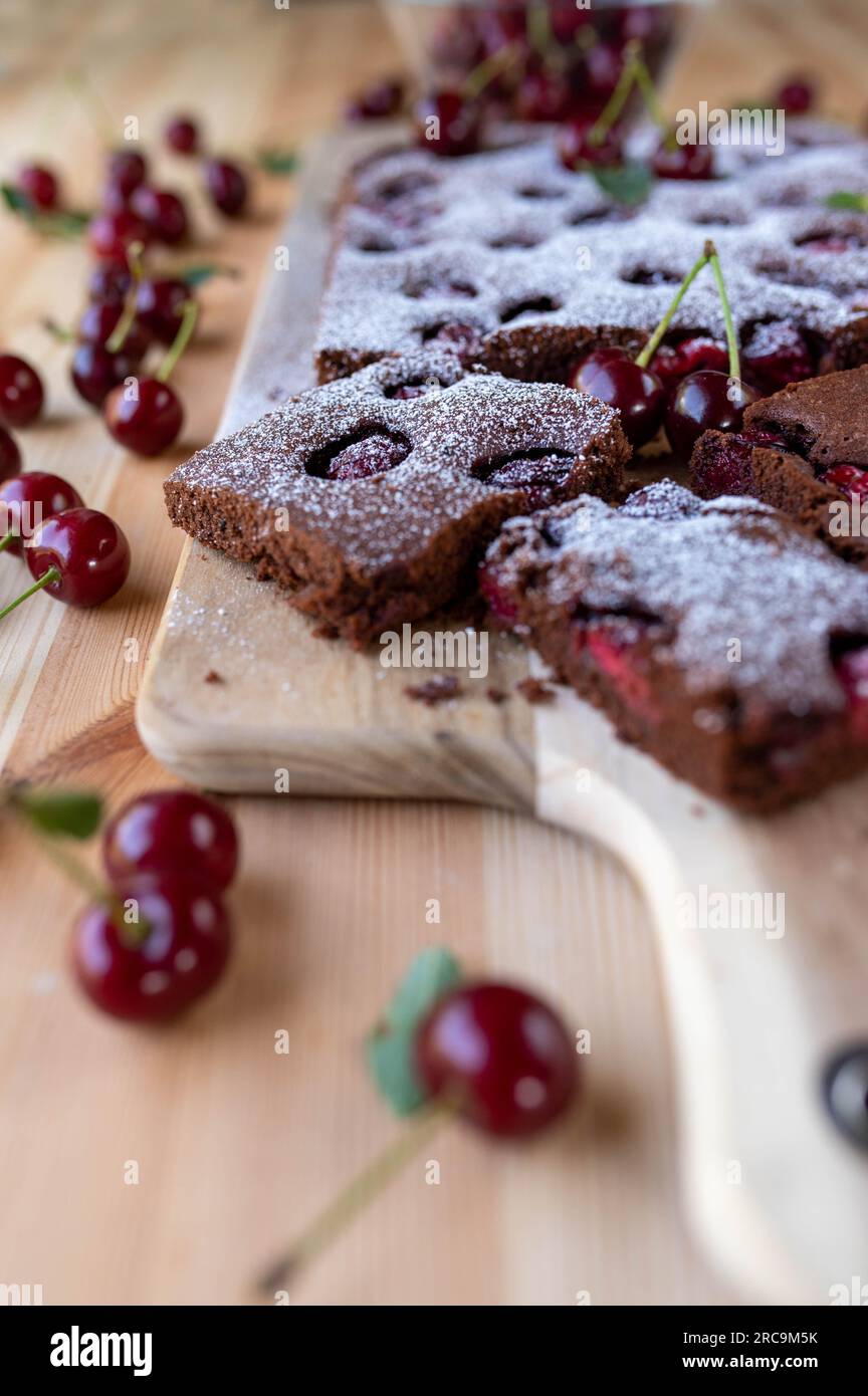 Schokoladenbrownies mit Kirschen und Puderzucker auf einem Holztisch Stockfoto