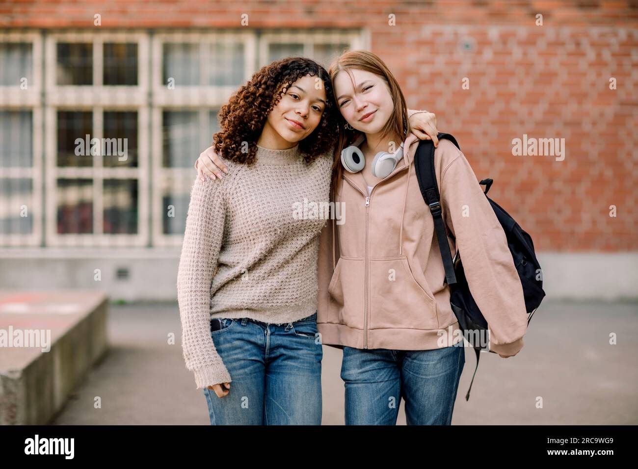 Porträt lächelnder Schülerinnen, die mit Armen auf dem High School Campus stehen Stockfoto