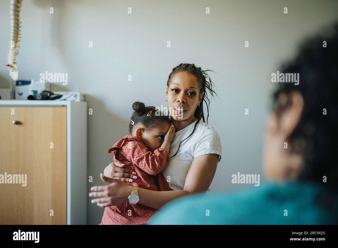 Frau mit kranker Tochter zur Diskussion mit Arzt in der Klinik Stockfoto