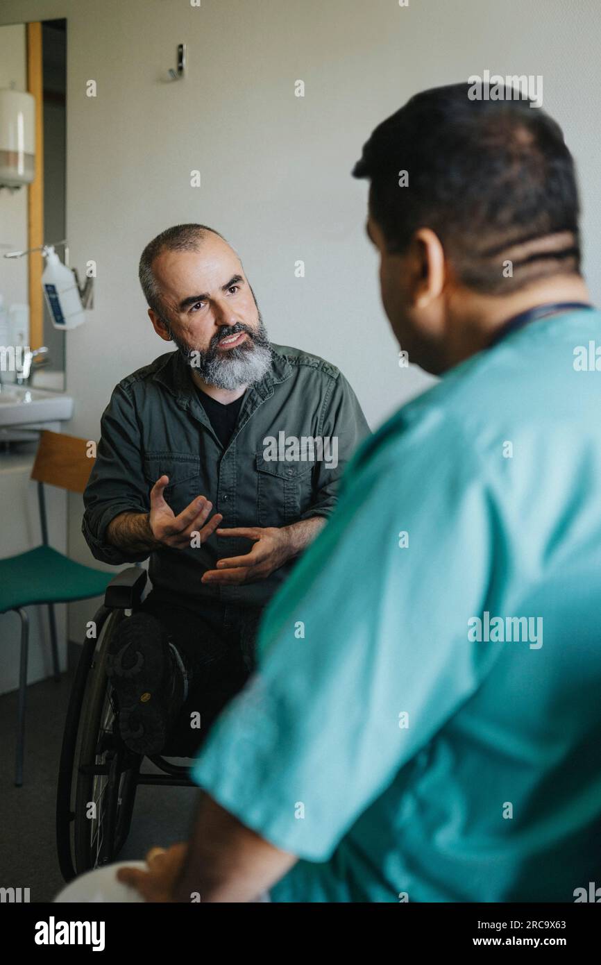 Reifer Patient im Rollstuhl erklärender Arzt in der Klinik Stockfoto