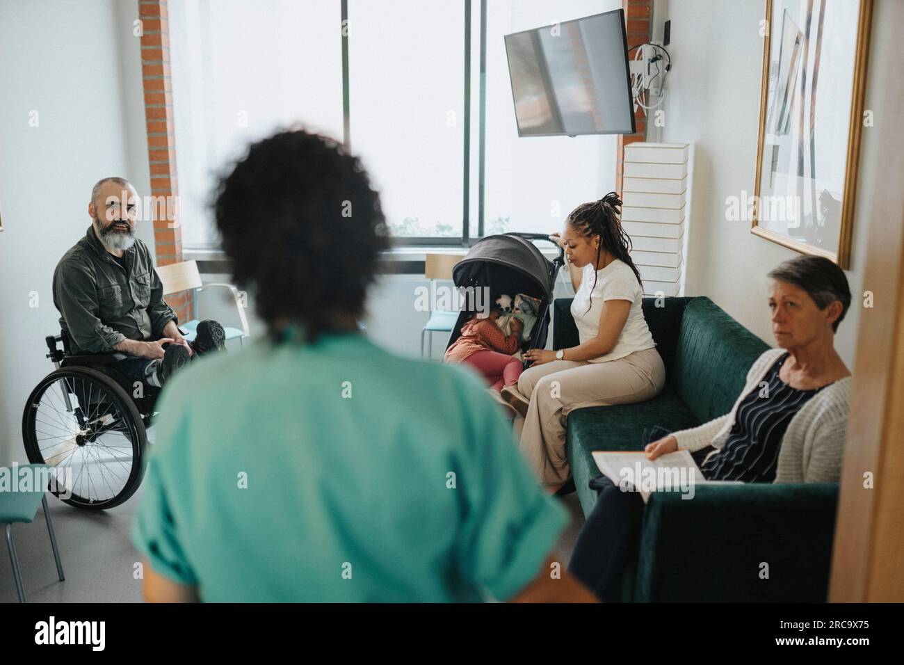 Patienten, die eine Krankenschwester im Wartezimmer des Krankenhauses betrachten Stockfoto