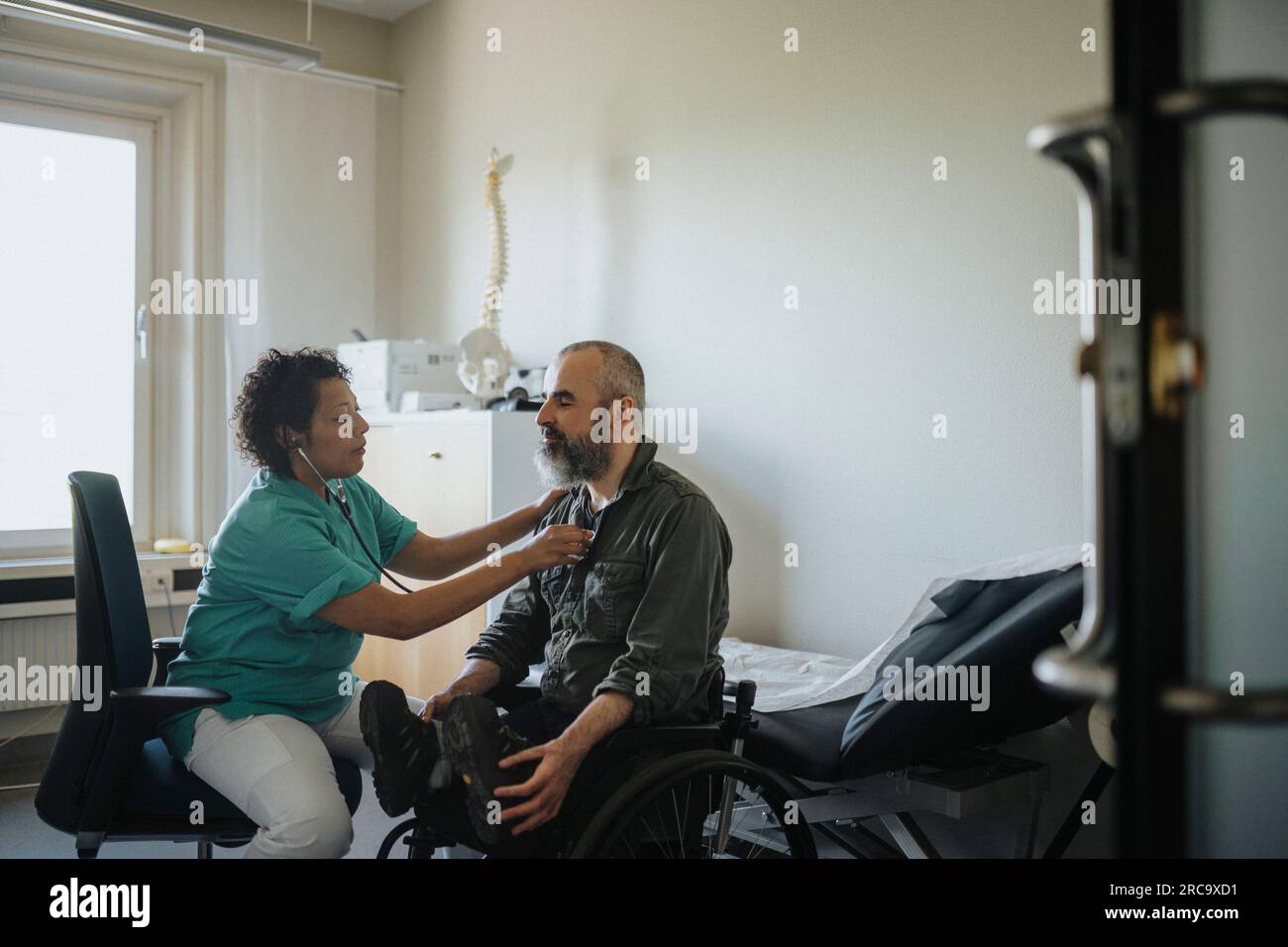 Arztin, die einen behinderten Mann in der Klinik untersucht Stockfoto