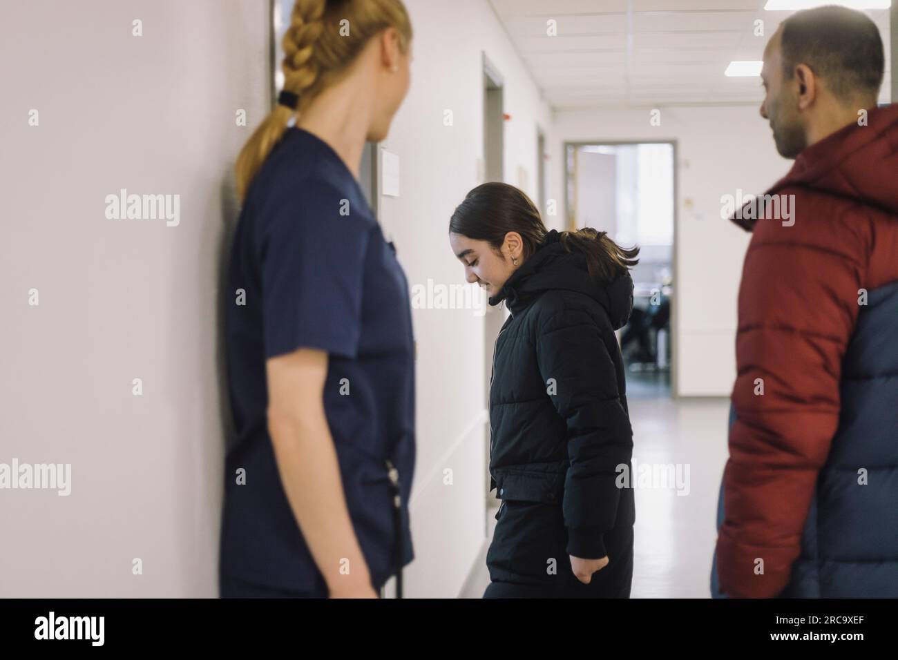 Seitenansicht einer Patientin, die mit dem Vater im Krankenhaus in die Sprechstunde kommt Stockfoto