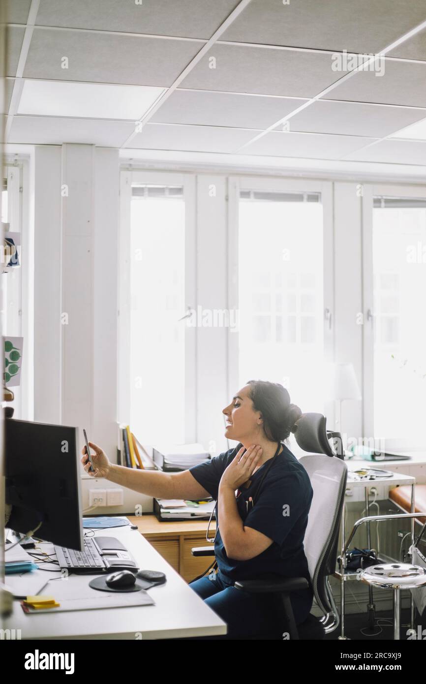 Krankenschwester, die online telefoniert, sitzt am Schreibtisch in der Klinik Stockfoto